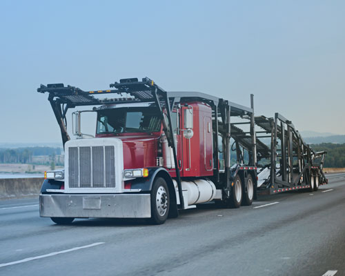 A large red semi truck driving down a highway.