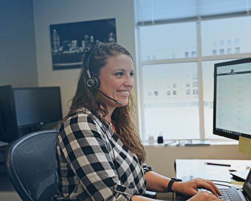 A Sherpa auto transport expert wearing a headset in front of a computer.