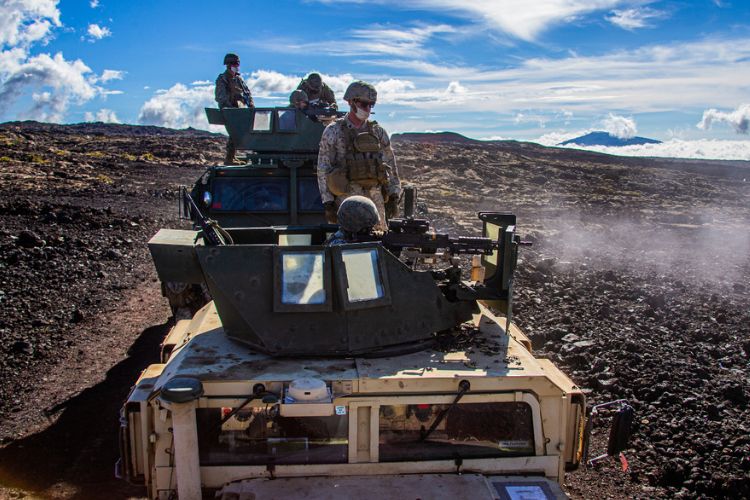 U.S. military personnel conduct training at Pohakuloa Training Area, operating an armored vehicle in a rugged volcanic landscape