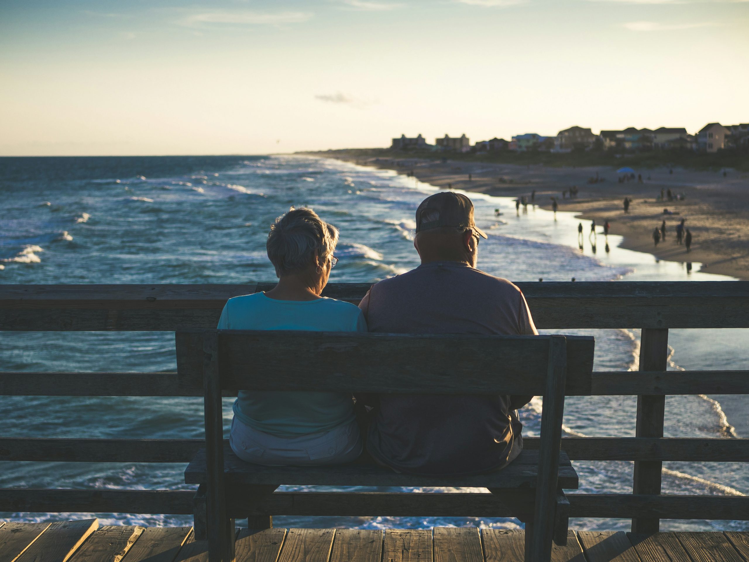 A retired couple sitting on a bench overlooking the water
