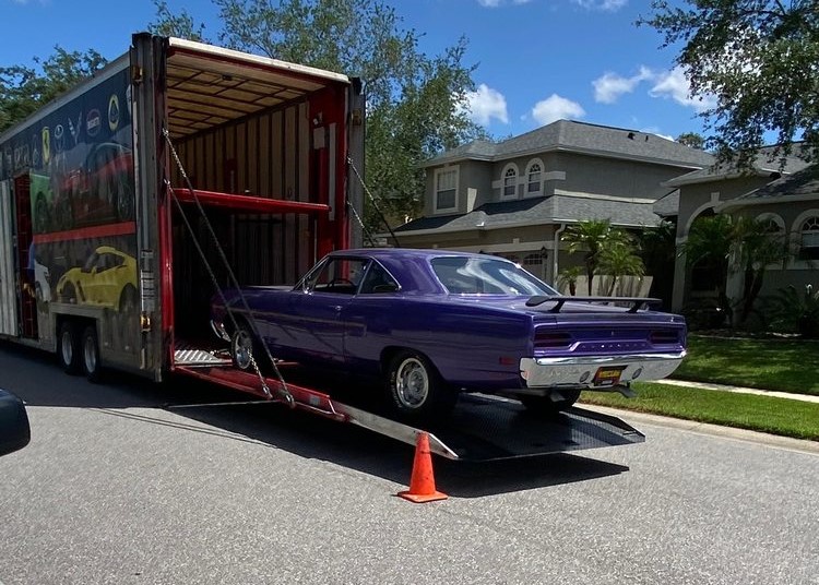 Purple classic car getting loaded into an enclosed trailer