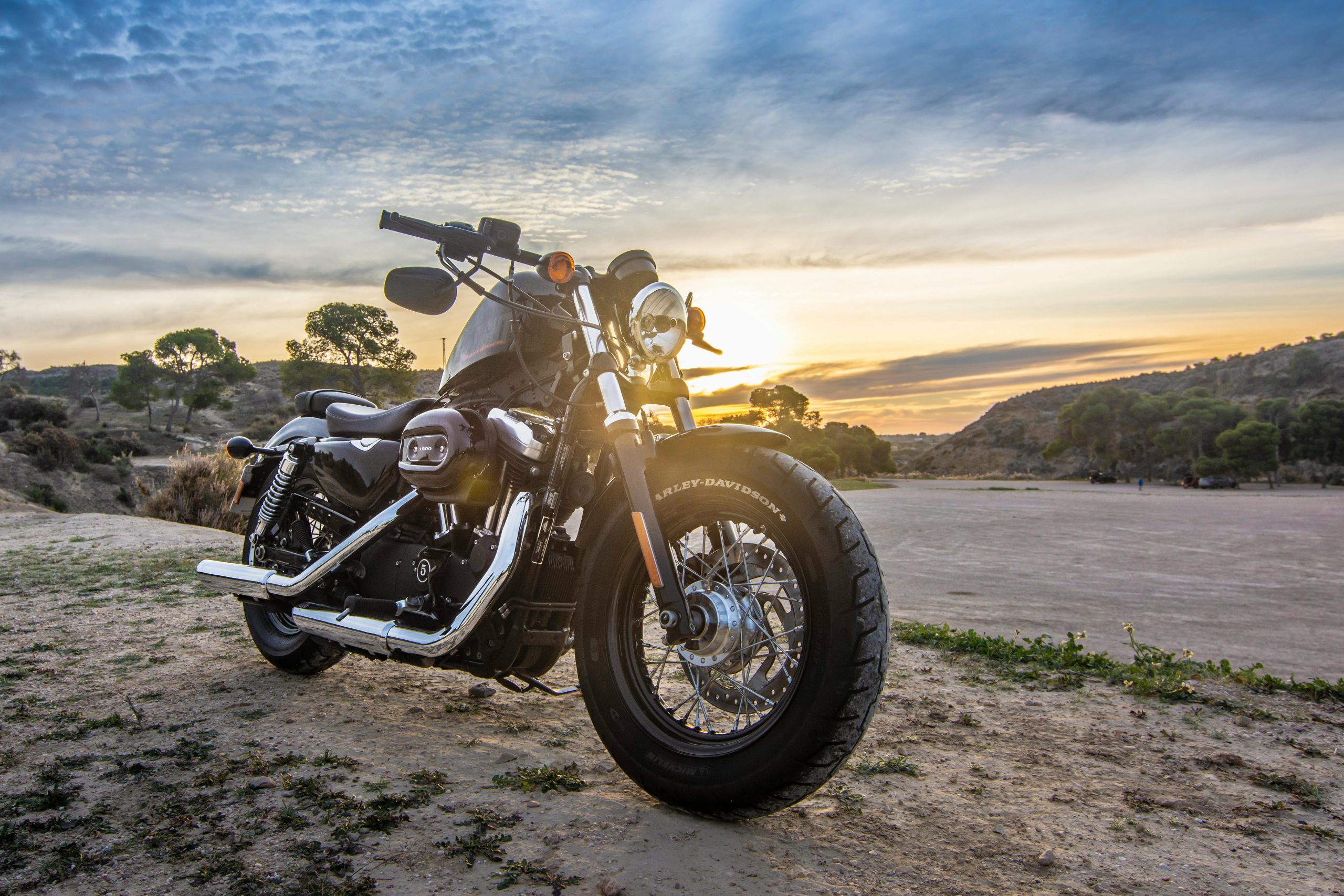 A motorcycle parked with a sunrise in the background.