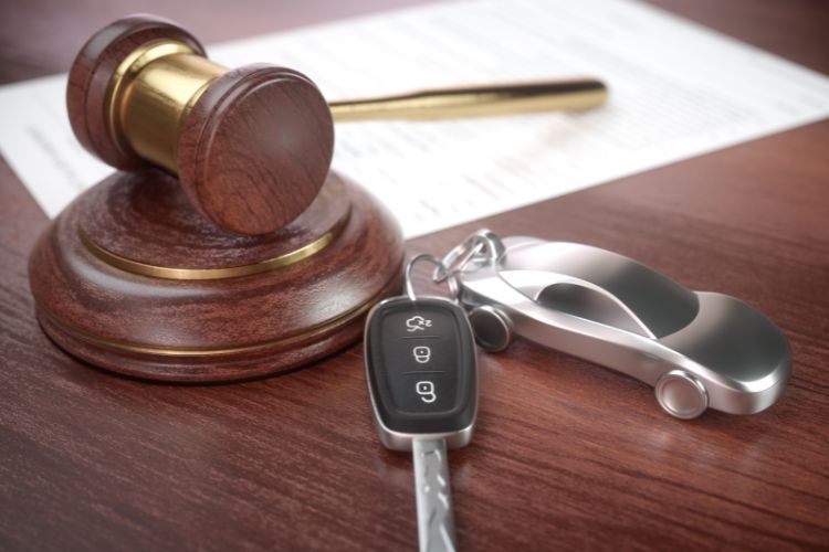 Car auction concept with a judge's gavel, car key, and metallic car keychain on a wooden desk, symbolizing classic car purchasing and legal transactions.