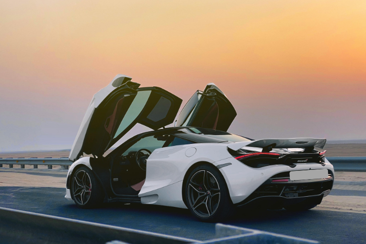 White sports car with doors open at sunset