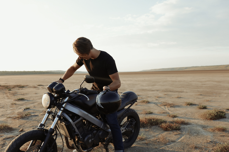 Man inspecting used motorcycle in desert