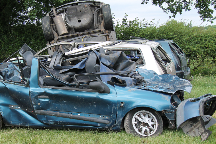 Stacked salvaged cars in grassy yard