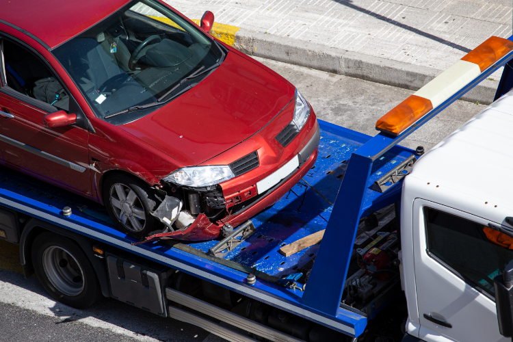 Damaged red car loaded on tow truck