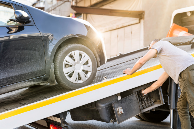 Worker loading black car onto flatbed