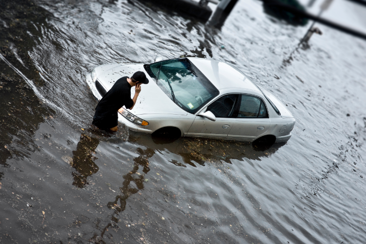 Man stranded beside flooded car street