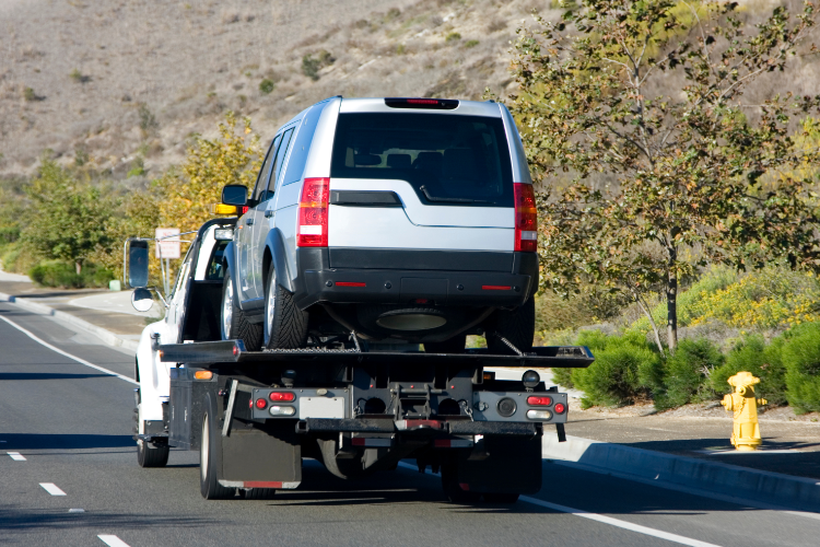 Flatbed Tow Truck Hauling Silver SUV