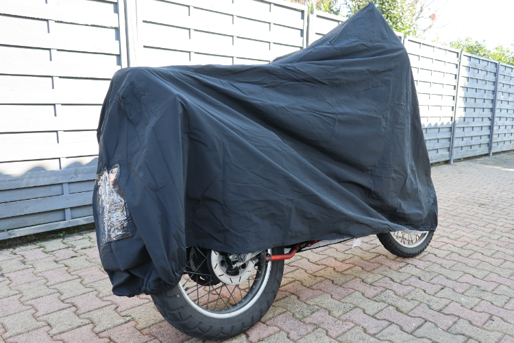 Covered Motorcycle Parked on Brick Pavement