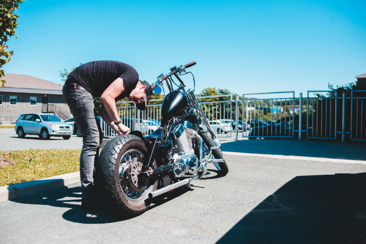 Man Inspecting Motorcycle Tire Outdoors