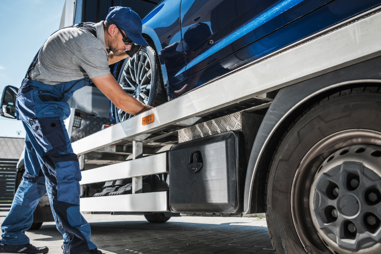 Car Shipping Technician Securing Vehicle On Trailer