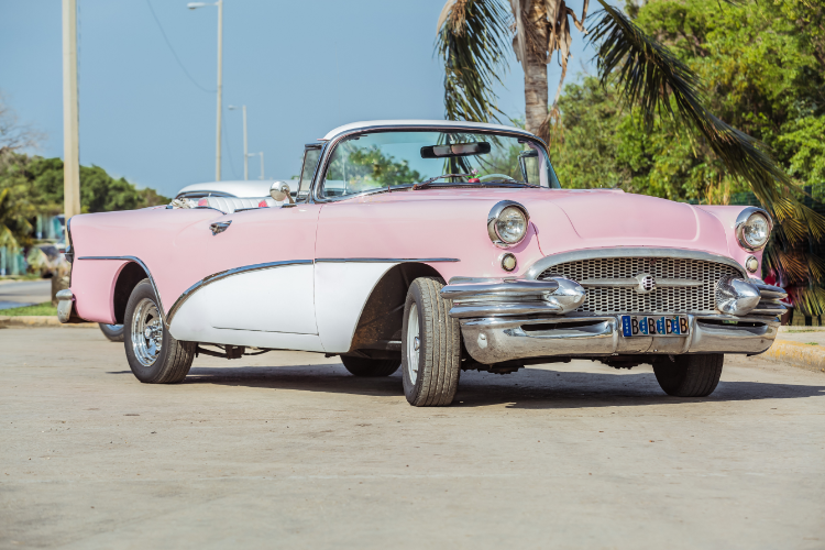 Pink white vintage convertible car under palm